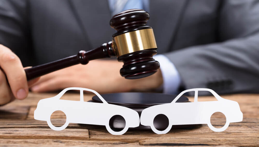 A gavel sits between car shapes, hinting at a legal car-related issue.