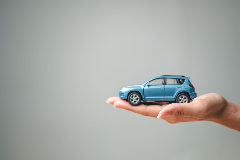 Illustration of a car resting in a person&rsquo;s hand, symbolizing how insurance adjusters determine fault in a Bakersfield car accident claim.