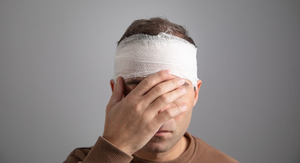 A man holding his bandaged head represents head trauma among the common Types of Injuries People Suffer in Truck Accidents.