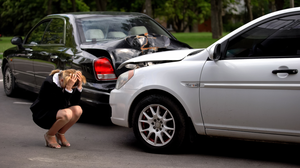 Upset woman sits near two crashed cars, showing a recent accident in Bakersfield.