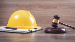 Yellow construction helmet on top of documents beside a judge’s gavel, symbolizing construction injury legal cases.