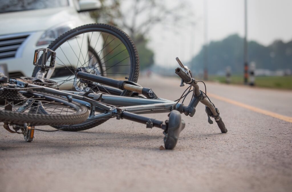 Damaged bicycle lying near a vehicle after a crash in Bakersfield, representing common bicycle accident scenarios and legal FAQs
