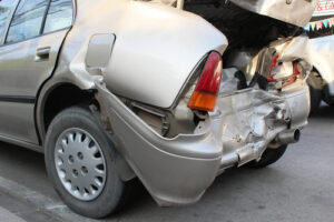 Rear-end damage to parked beige sedan after car accident in Bakersfield