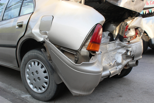 Rear-end damage to parked beige sedan after car accident in Bakersfield