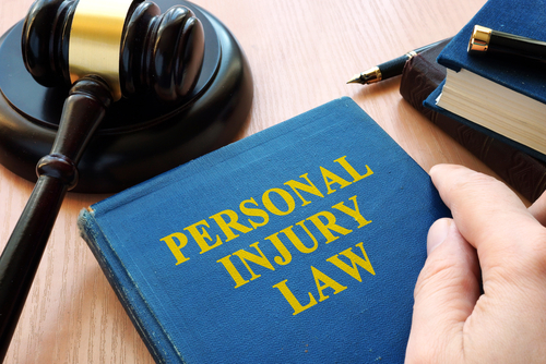 Close-up of a personal injury law book with a gavel on a wooden desk.