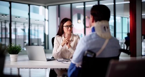 Female lawyer meeting with an injured client wearing a neck brace in an office.