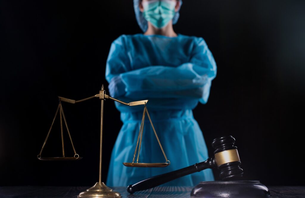 Un profesional sanitario ante la justicia, con una balanza y un mazo, que ilustra la representación especializada que ofrece el bufete de abogados de Mickey Fine en casos de homicidio culposo en Bakersfield.