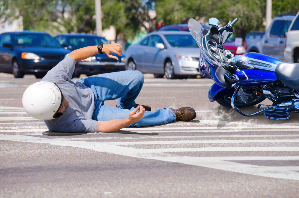 A motorcyclist lying on the pavement next to a fallen blue bike, demonstrating the aftermath of a "didn't see the motorcycle" accident in Bakersfield.