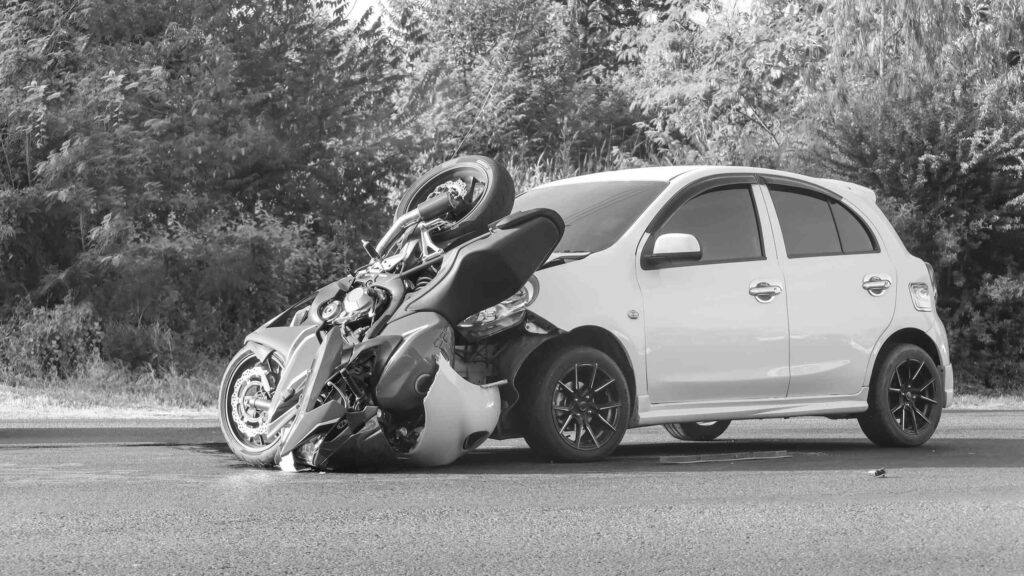 A black and white photo of a motorcycle crashed into the front of a sedan, illustrating a common collision where a driver failed to keep a proper lookout.