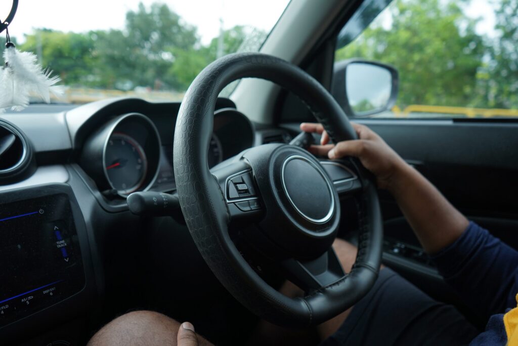 Close-up of a rideshare driver's hands navigating a steering wheel while on the road, illustrating the standard operation of motor vehicles involved in claims managed by Bakersfield Uber accident lawyers.