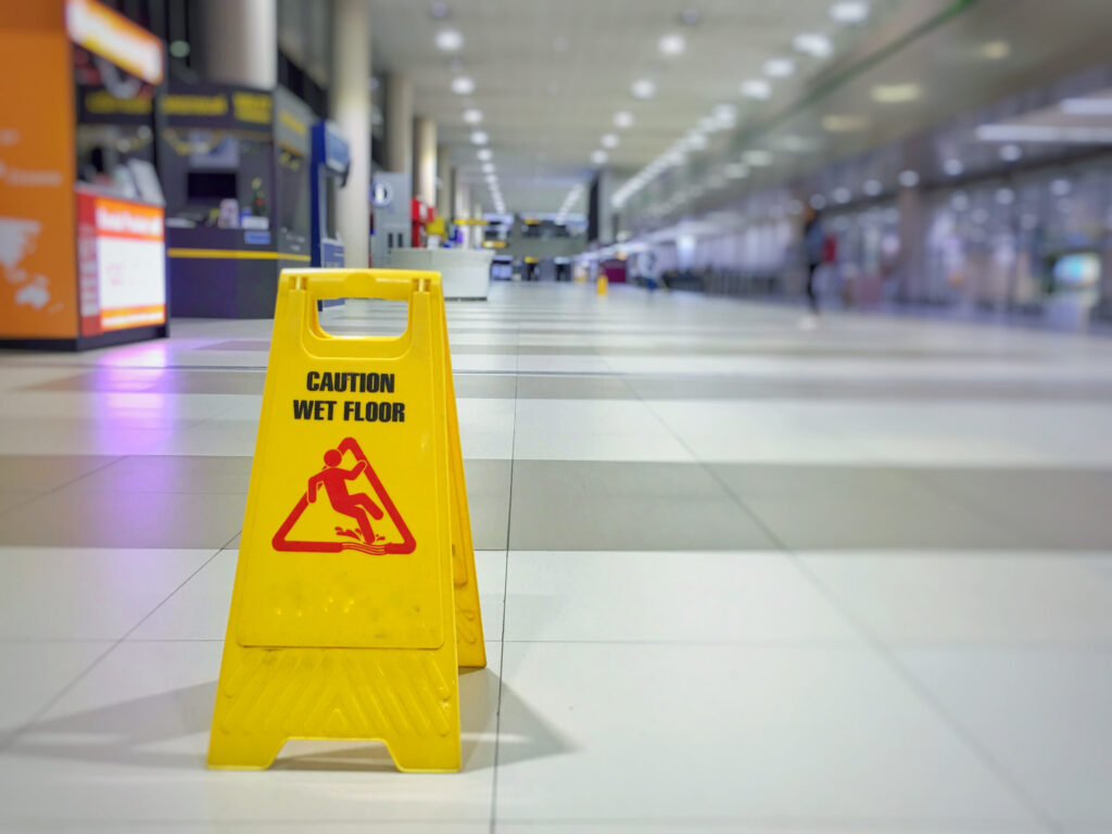 A yellow "Caution Wet Floor" sign on a tiled public floor, illustrating a slip and fall hazard handled by Bakersfield Premises Liability Lawyers.