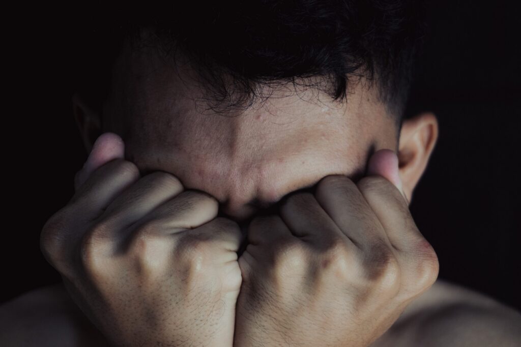 A man covering his face in anguish illustrates psychological trauma related to can you recover emotional distress damages after a car accident in California.