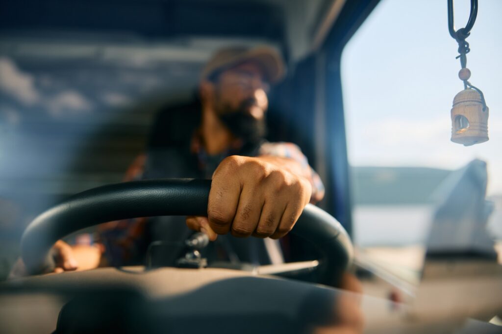 A driver holding the steering wheel inside a semi truck cab highlights key factors in CDL Violations and Driver Qualifications: Negligence in a Bakersfield Truck Accident.