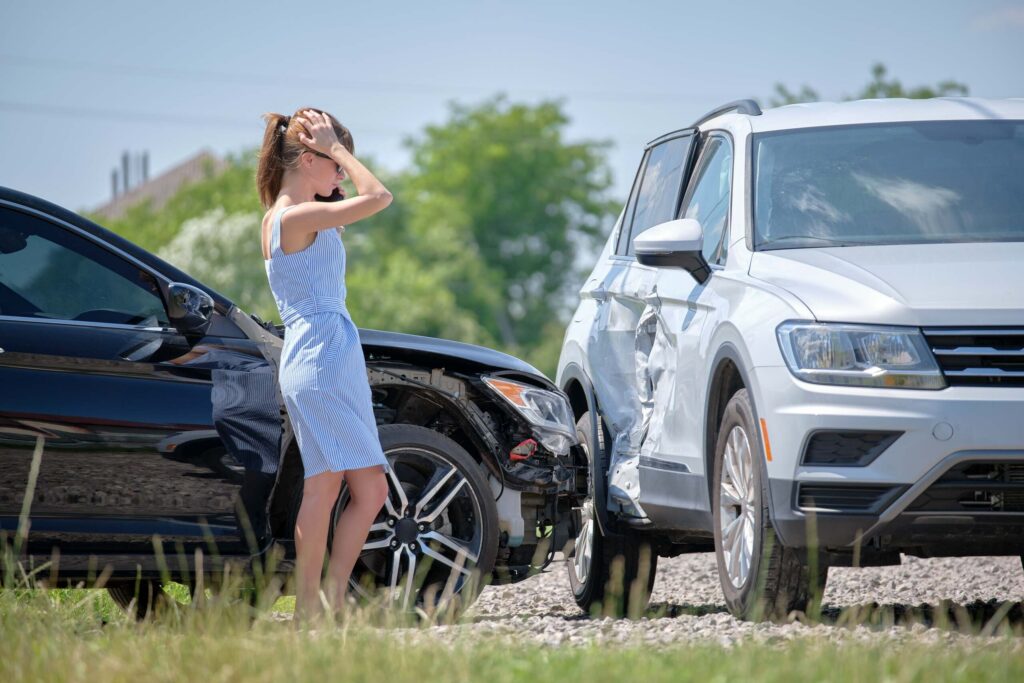 A stressed woman calling on her phone after a two car crash highlights how long do you have to report a car accident to your insurance in California.