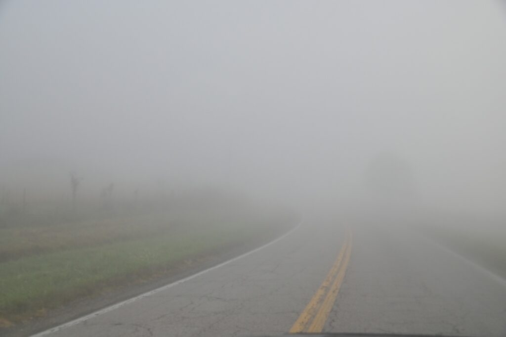 Dense mist covering an empty two lane road illustrates low visibility during Tule Fog and Truck Accidents on Highway 99 and I-5 in Kern County.